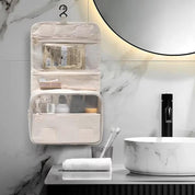Organizer da viaggio appeso in bagno moderno, con tasche trasparenti contenenti articoli da toeletta. Design elegante, ideale per viaggi e organizzazione.