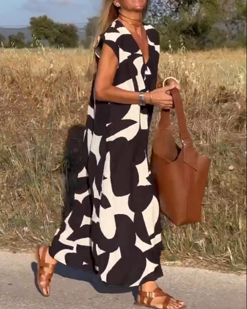 Donna con abito lungo bianco e nero astratto, borsa in pelle marrone, sandali marroni, cammina su strada di campagna. Moda estiva, stile casual.