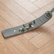 Mocio in microfibra grigio su pavimento in legno chiaro, raccoglie detriti e foglie. Pulizia efficace, accessorio domestico essenziale.