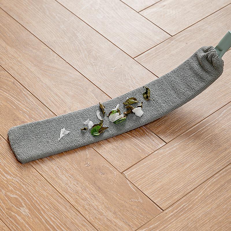 Mocio in microfibra grigio su pavimento in legno chiaro, raccoglie detriti e foglie. Pulizia efficace, accessorio domestico essenziale.