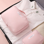 Set da viaggio rosa con borsa trucco e camicia bianca in valigia aperta. Accessori organizzazione bagaglio, ideale per viaggi e cosmetici.