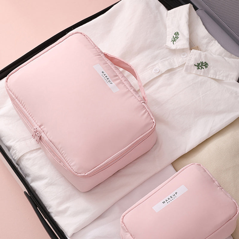 Set da viaggio rosa con borsa trucco e camicia bianca in valigia aperta. Accessori organizzazione bagaglio, ideale per viaggi e cosmetici.