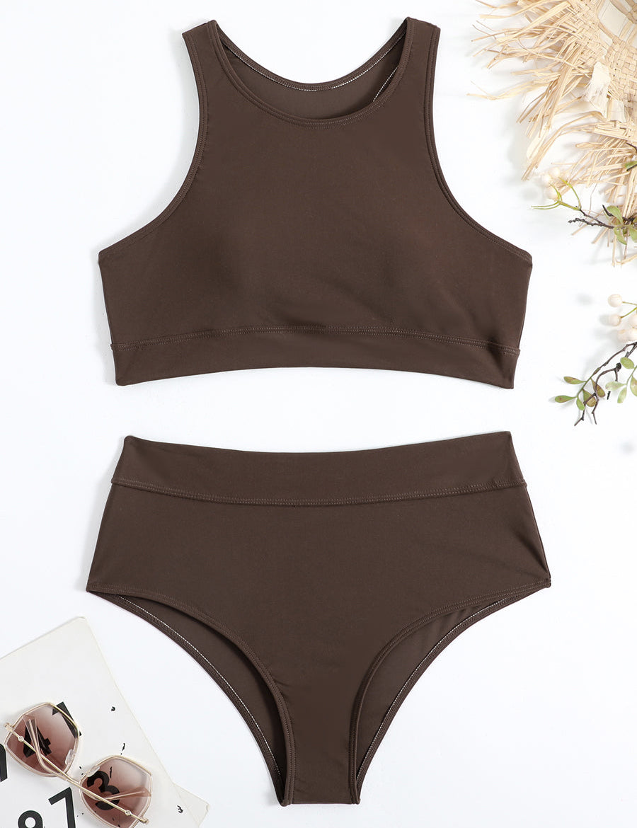 Costume da bagno donna marrone scuro a due pezzi, top sportivo e slip a vita alta, su sfondo bianco con occhiali da sole e decorazioni naturali.