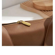 Borsa in pelle marrone con cerniera dorata, design elegante e moderno, accessorio moda donna, ideale per look casual e formali.