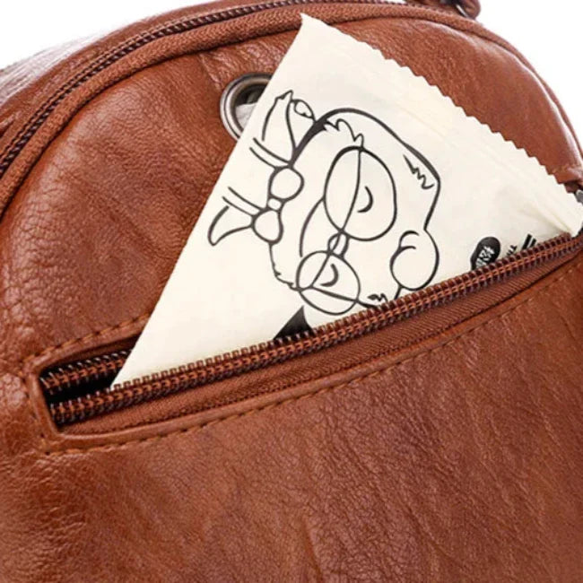 Zaino in pelle marrone con tasca aperta contenente un pacchetto illustrato. Accessorio moda, zaino casual, design elegante.
