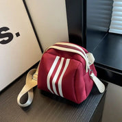 Borsa a tracolla rossa con strisce bianche, design moderno, chiusura a zip, ideale per moda casual. Accessorio elegante e funzionale.