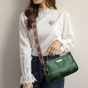 Donna con borsa a tracolla verde in pelle, decorata con motivo a quadri bianchi, indossa camicia bianca elegante con pizzo. Accessorio moda femminile.