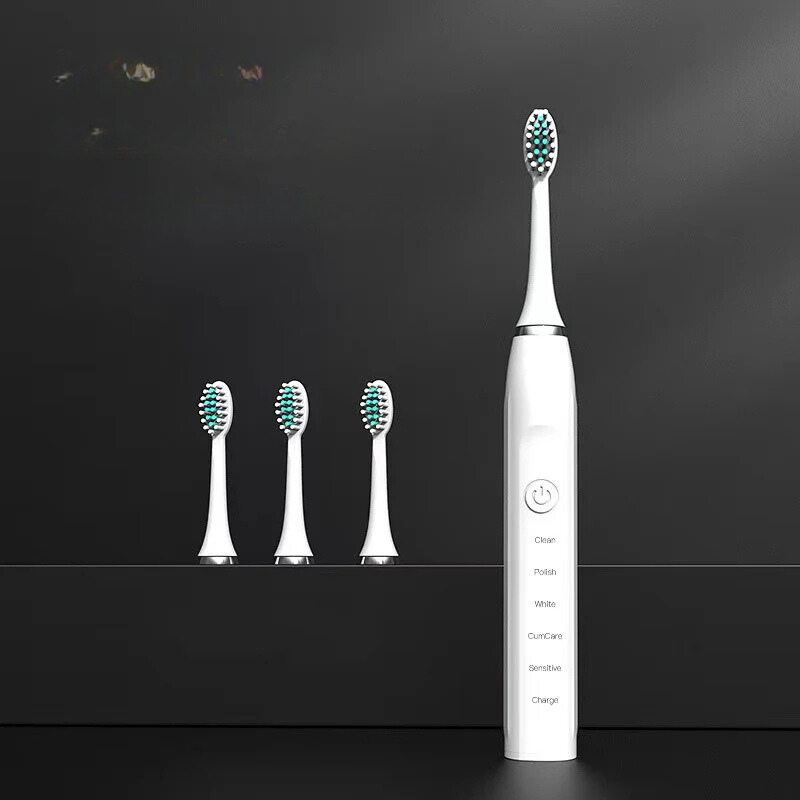 Spazzolino elettrico bianco con tre testine di ricambio su sfondo nero. Design moderno, setole verdi, ideale per igiene orale avanzata.