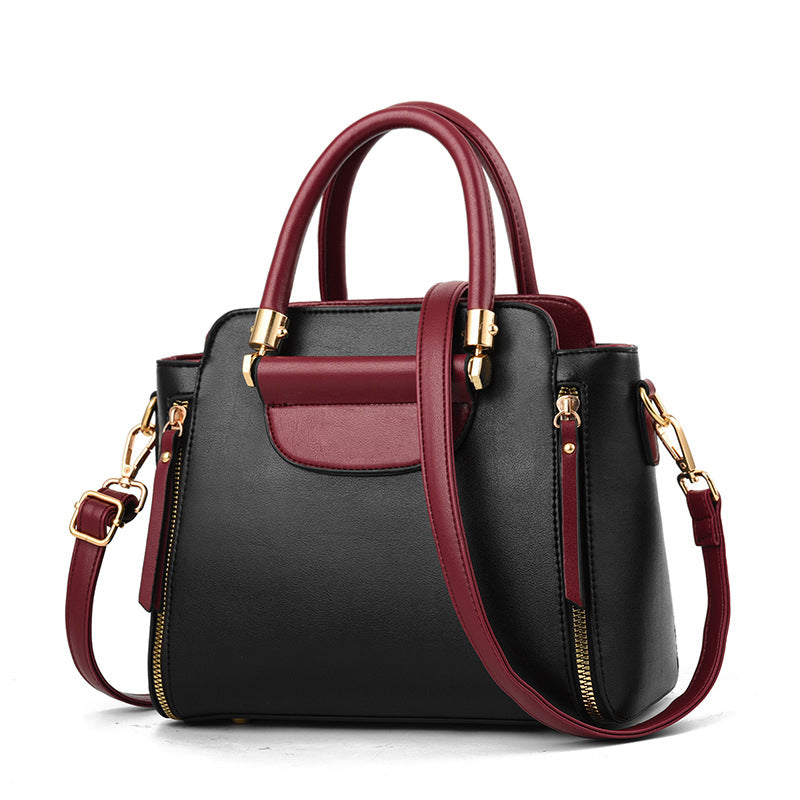 Borsa a mano in pelle nera e bordeaux con dettagli dorati, tracolla regolabile, chiusura a zip, design elegante e moderno.