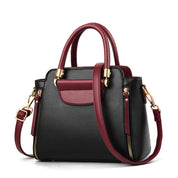 Borsa a mano in pelle nera e bordeaux con dettagli dorati, tracolla regolabile, chiusura a zip, design elegante e moderno.