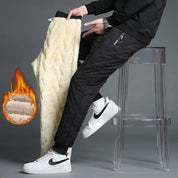 Pantaloni invernali termici da uomo, foderati in pile, colore nero, con zip, mostrati su sgabello trasparente. Scarpe sportive bianche.