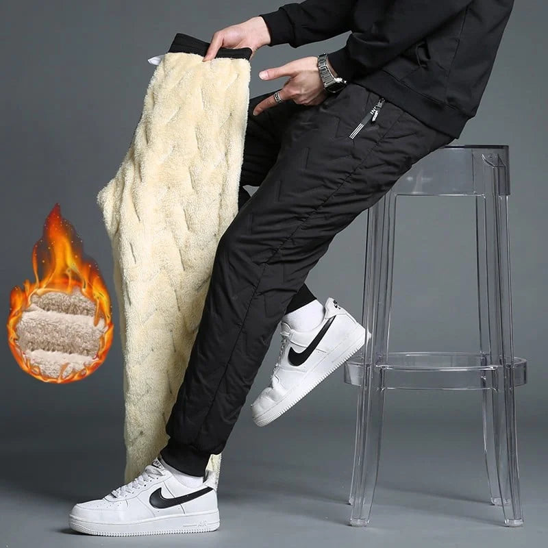 Pantaloni invernali termici da uomo, foderati in pile, colore nero, con zip, mostrati su sgabello trasparente. Scarpe sportive bianche.
