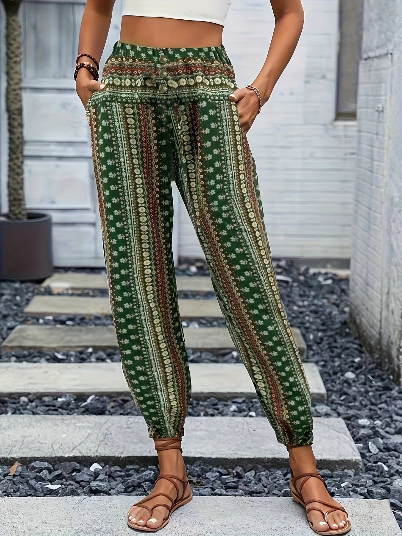 Pantaloni boho verdi a righe floreali, vita alta, tasche laterali, indossati con sandali marroni. Stile casual estivo per donna.