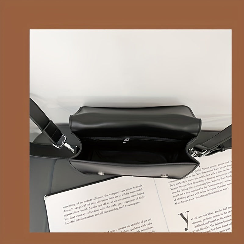 Borsa a tracolla nera in pelle, vista dall'alto, con interno spazioso e chiusura a zip, su sfondo di pagine di libro. Elegante e moderna.