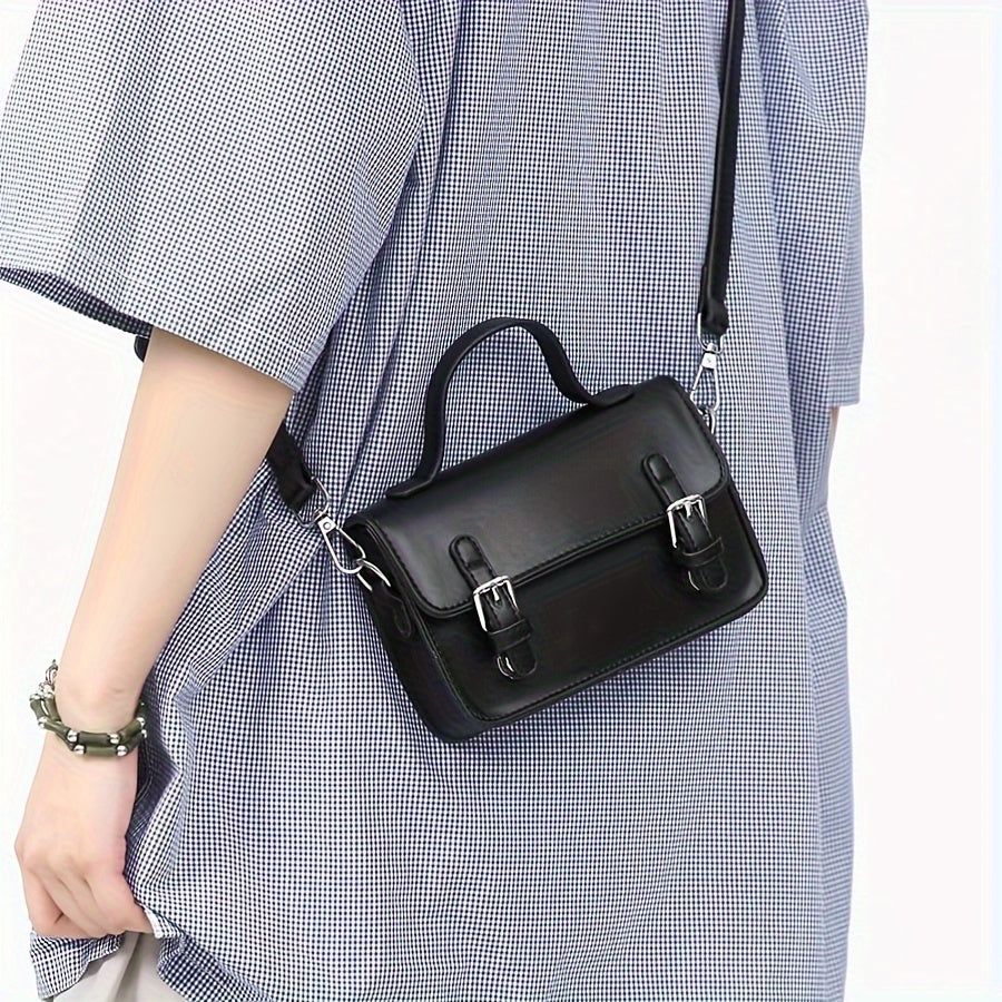 Borsa a tracolla nera in pelle, design elegante con fibbie argentate, indossata su abito a quadri. Accessorio moda donna, stile casual chic.