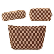 Set di tre pochette a scacchi marroni e beige, eleganti e versatili, ideali per cosmetici e accessori. Design moderno e pratico.