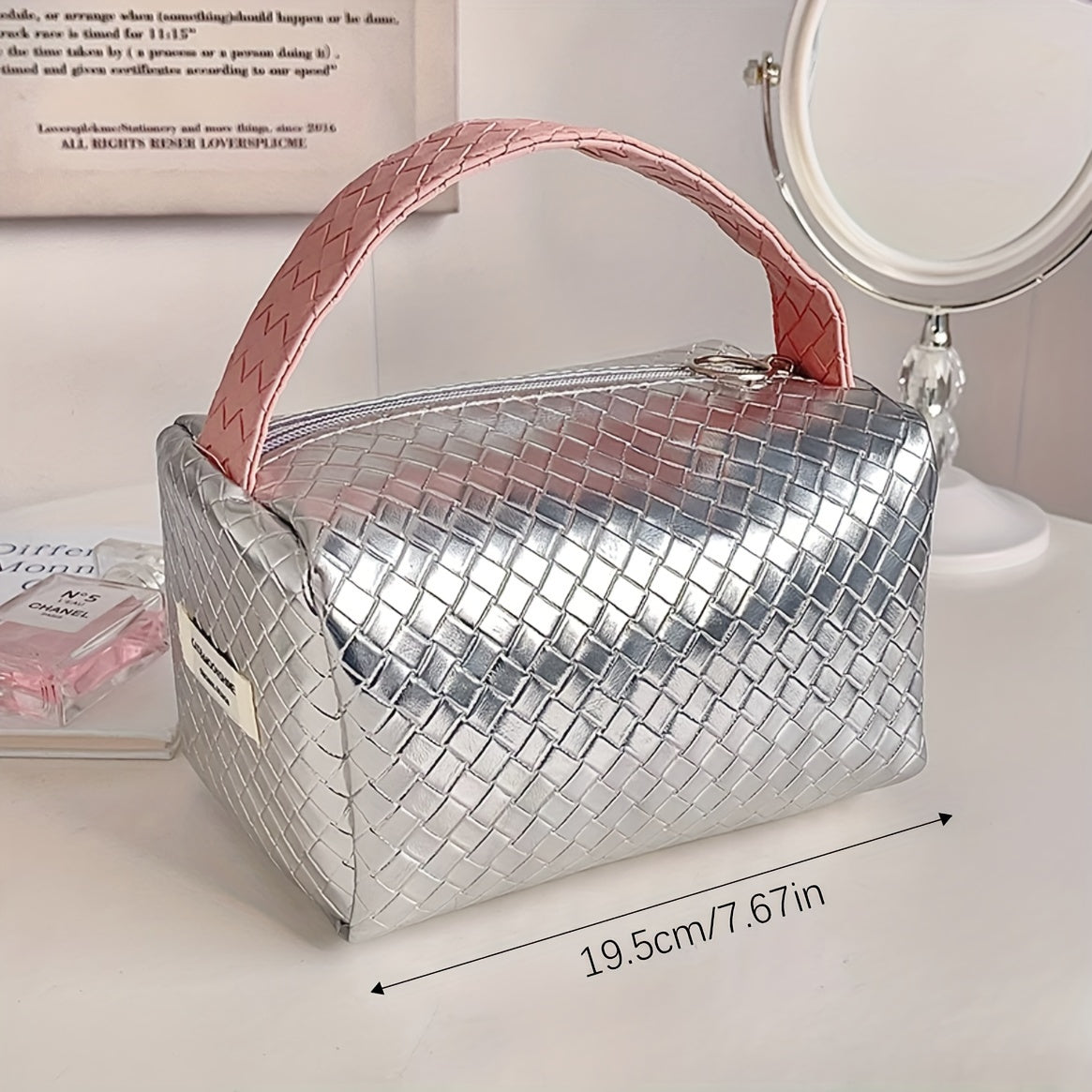 Borsa cosmetica argento intrecciata, manico rosa, dimensioni 19,5 cm, su tavolo con specchio. Elegante organizer da viaggio per trucco.