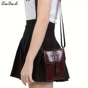 Borsa a tracolla in pelle marrone scuro, indossata da una persona con gonna nera e maglietta bianca. Accessorio moda elegante e pratico.