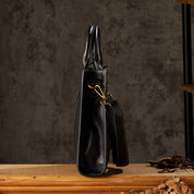 Borsa a mano in pelle nera, design elegante, dettagli dorati, su tavolo in legno. Accessorio moda donna, stile sofisticato e moderno.