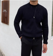 Giacca nera uomo, zip frontale, indossata con pantaloni scuri. Moda maschile elegante, abbigliamento casual autunnale. Sfondo bianco minimalista.