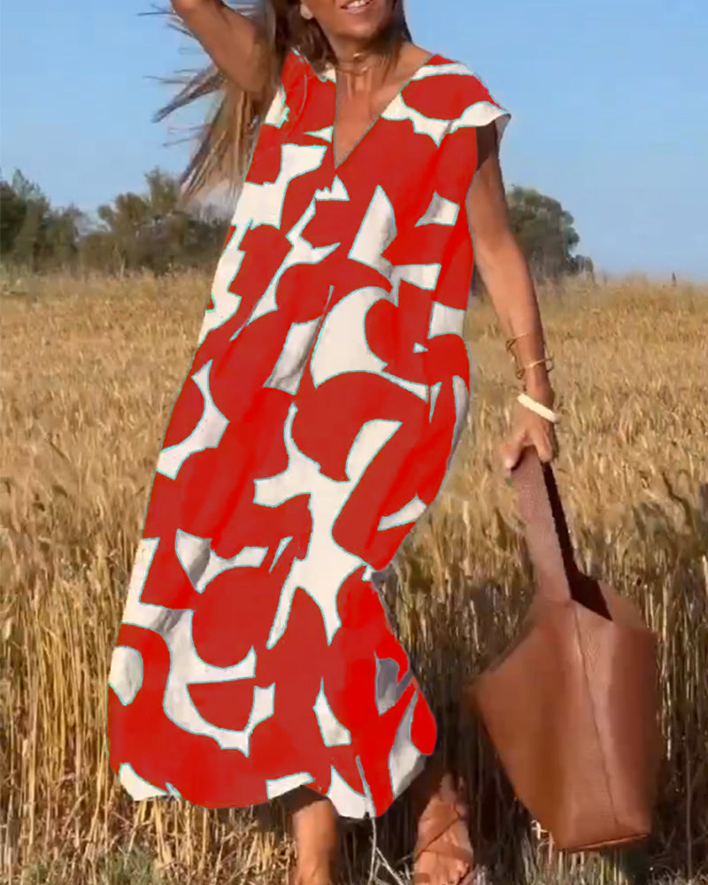 Donna in abito lungo rosso e bianco con motivo astratto, in un campo di grano, borsa marrone, estate, moda femminile, stile casual.