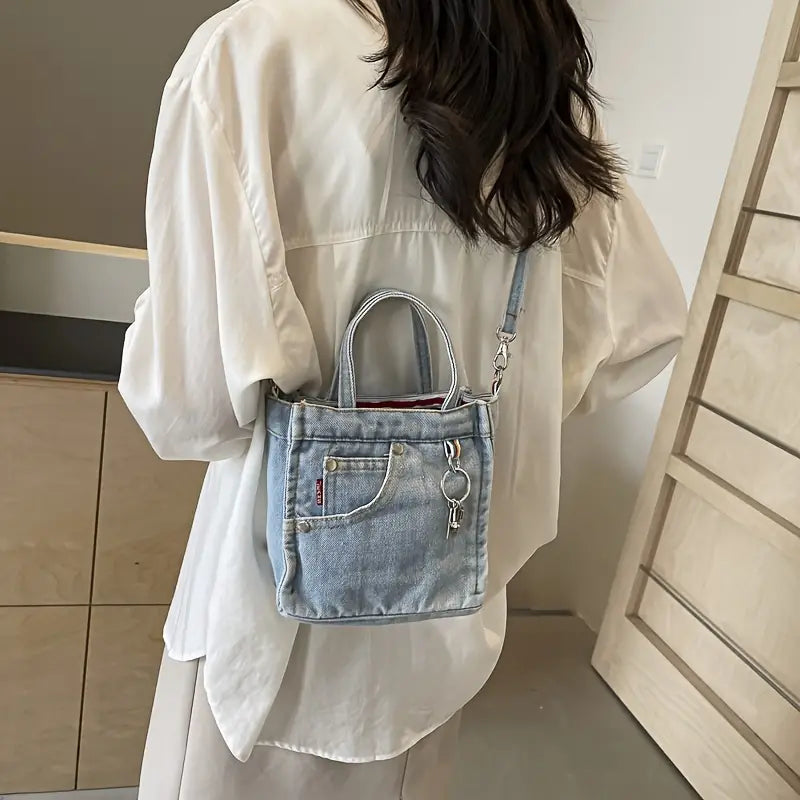 Donna con camicia bianca indossa borsa a tracolla in denim con tasca frontale e portachiavi. Stile casual, moda femminile, accessori trendy.