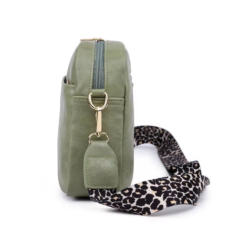 Borsa a tracolla verde oliva in pelle sintetica con cerniera, dettagli dorati e tracolla regolabile leopardata. Accessorio moda donna elegante.