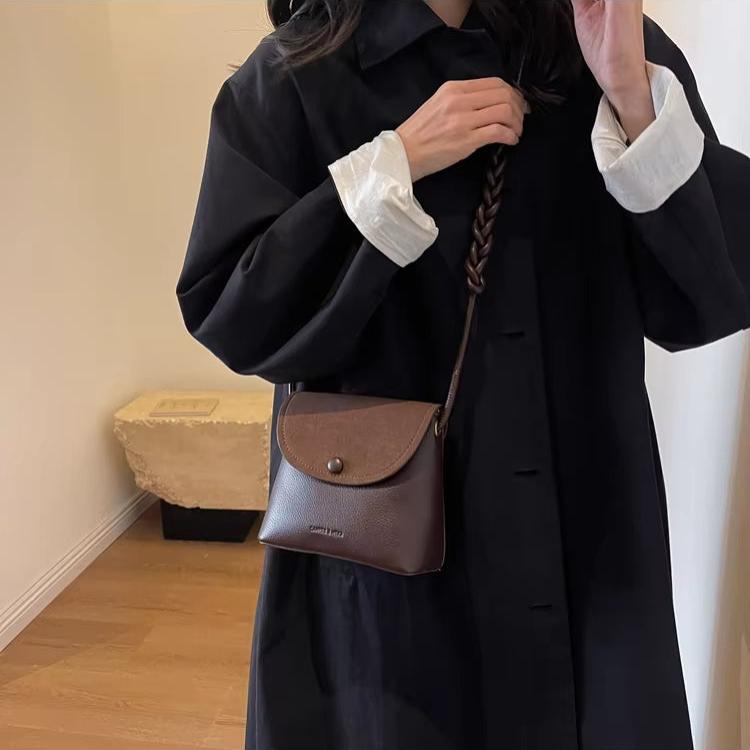 Donna con cappotto nero e borsa a tracolla in pelle marrone. Moda autunnale, accessori eleganti, stile casual chic.