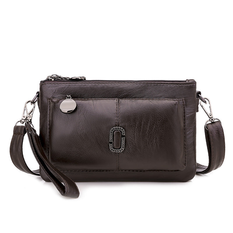 Borsa a tracolla in pelle nera con tasca frontale, cerniera superiore e dettagli metallici. Elegante accessorio moda donna.