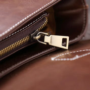 Borsa in pelle marrone con cerniera dorata, dettaglio chiusura. Accessorio moda elegante, alta qualità, ideale per uomo e donna.