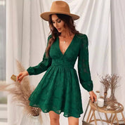 Donna con abito verde elegante, cappello beige, in posa accanto a decorazioni boho-chic. Moda femminile, stile autunnale, abbigliamento trendy.