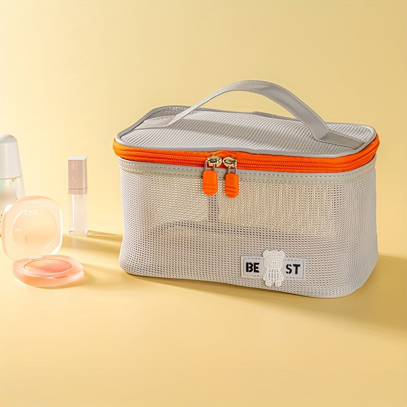 Borsa cosmetica in rete grigia con cerniera arancione, manico superiore, su sfondo giallo. Accessori trucco accanto. Organizzatore da viaggio elegante.