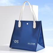 Borsa tote blu con manici bianchi, design moderno, numero 05, scritta "Have a Good Trip", sfondo cielo azzurro. Accessorio moda elegante.