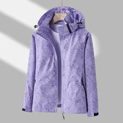 Giacca impermeabile viola con cappuccio, motivo foglie, chiusura zip, tasche laterali, ideale per outdoor e sport. Abbigliamento donna autunno.