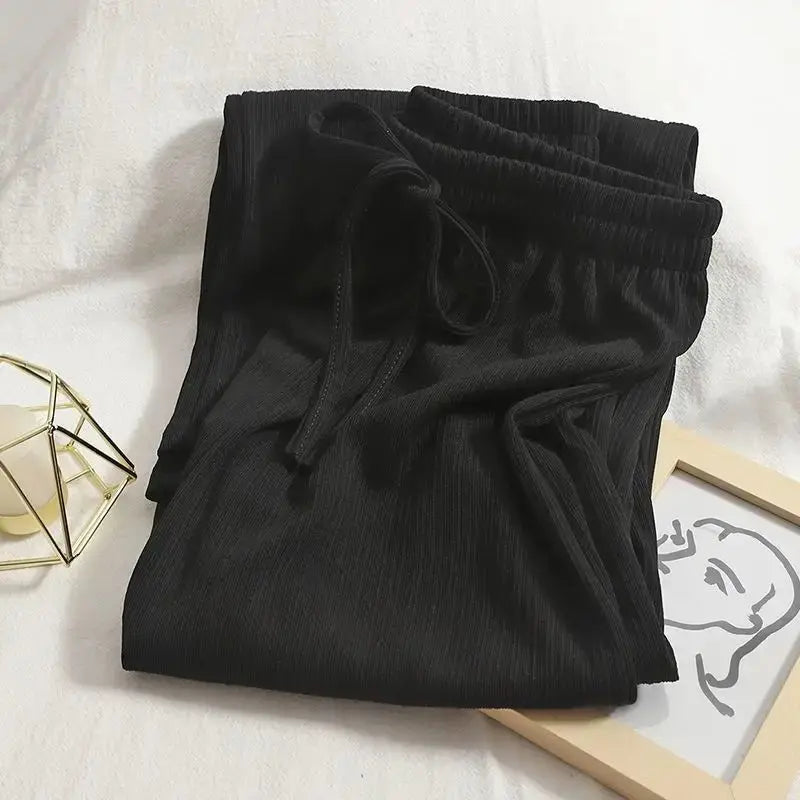 Pantaloni neri in tessuto a coste con elastico in vita e laccio, su sfondo chiaro. Abbigliamento casual, moda donna, comfort quotidiano.