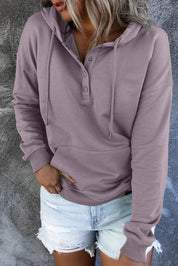 Felpa con cappuccio viola chiaro da donna, bottoni frontali, tasca a marsupio, abbinata a shorts di jeans strappati. Look casual e moderno.