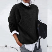 Donna con maglione nero oversize, camicia bianca e borsa nera. Moda casual autunnale, abbigliamento femminile elegante e confortevole.