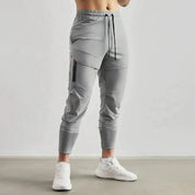 Pantaloni sportivi grigi da uomo, design moderno con tasca laterale, elastico in vita e caviglie, ideali per fitness e tempo libero.