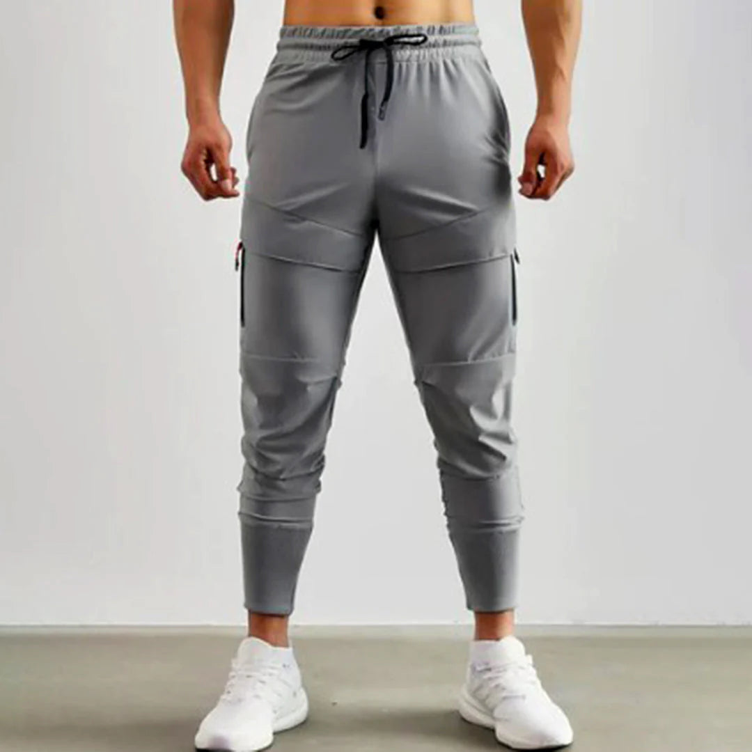 Pantaloni sportivi grigi da uomo, tasche laterali, elastico in vita, stile casual, perfetti per palestra e attività all'aperto.