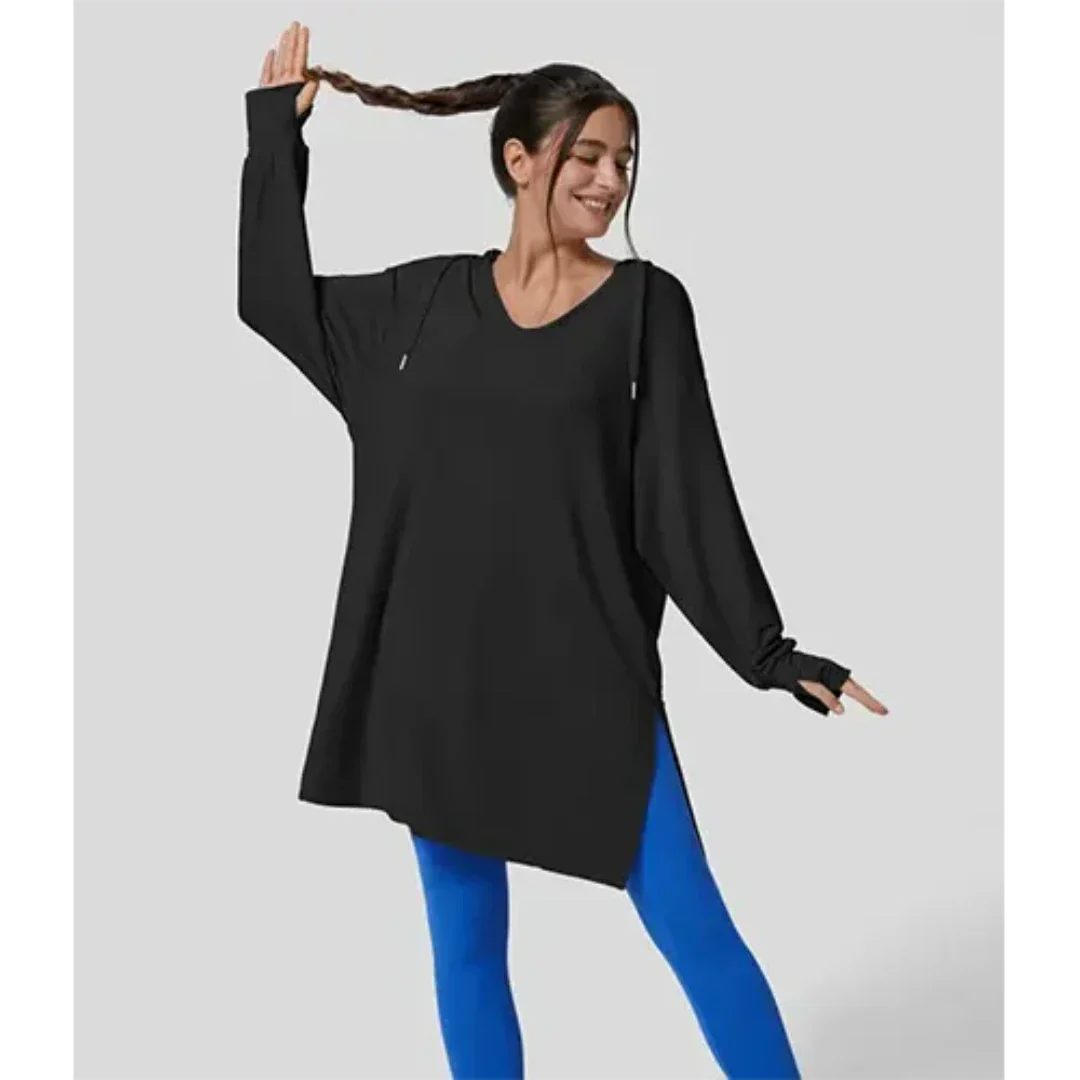Donna sorridente in tunica nera oversize e leggings blu, posa dinamica. Abbigliamento casual, moda donna, comfort, stile moderno.