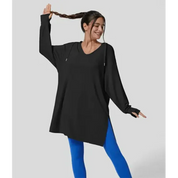 Donna sorridente in tunica nera oversize e leggings blu, posa dinamica. Abbigliamento casual, moda donna, comfort, stile moderno.