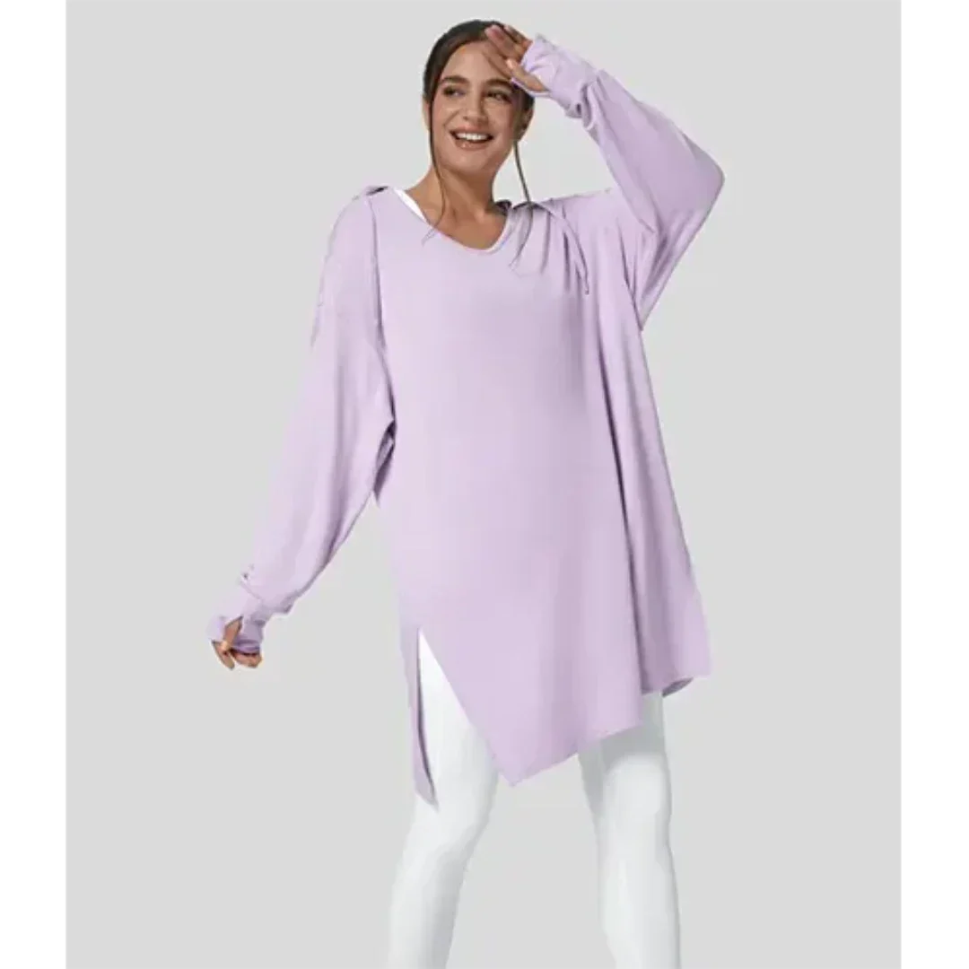 Donna sorridente con tunica oversize lilla e leggings bianchi. Moda casual femminile, abbigliamento comodo, stile autunnale.