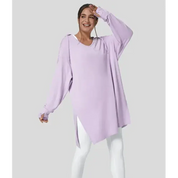 Donna sorridente con tunica oversize lilla e leggings bianchi. Moda casual femminile, abbigliamento comodo, stile autunnale.