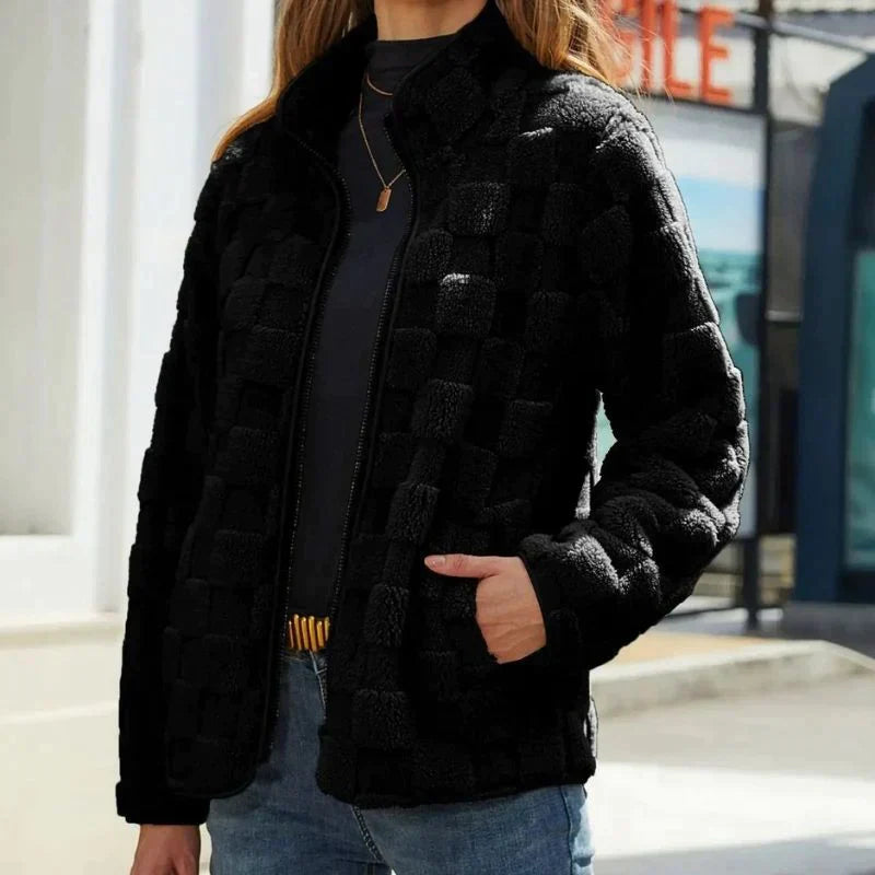 Giacca nera in pile a quadri, donna, con zip frontale, indossata su maglia grigia e jeans. Moda autunnale, abbigliamento casual elegante.