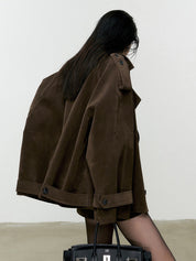 Donna con cappotto marrone oversize, capelli lunghi, borsa nera. Moda autunno, stile casual chic. Sfondo neutro.