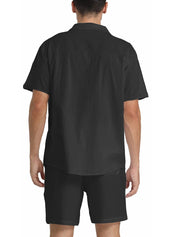Camicia uomo nera a maniche corte, vista posteriore, tessuto leggero, ideale per look casual estivi. Abbinata a pantaloncini neri coordinati.
