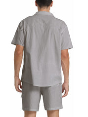 Uomo in completo estivo grigio chiaro, camicia a maniche corte e pantaloncini coordinati. Moda casual estiva, abbigliamento maschile elegante.