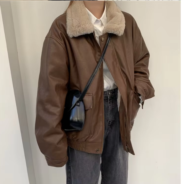 Giacca in pelle marrone con colletto in pelliccia sintetica, indossata su camicia bianca e jeans neri, borsa a tracolla nera. Moda autunnale casual.