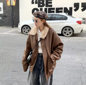 Giacca di pelle marrone con colletto in pelliccia sintetica, indossata da una persona in strada. Moda urbana, stile casual, cappello a quadri.