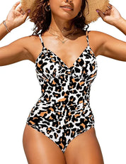 Donna in costume intero leopardato, spalline sottili, cappello di paglia, collane dorate. Moda mare estiva, stile animalier, abbigliamento da spiaggia.